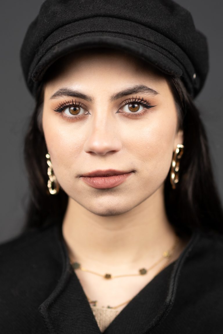 Portraitfoto einer jungen Frau mit dunklen Haaren und Schirmmütze.