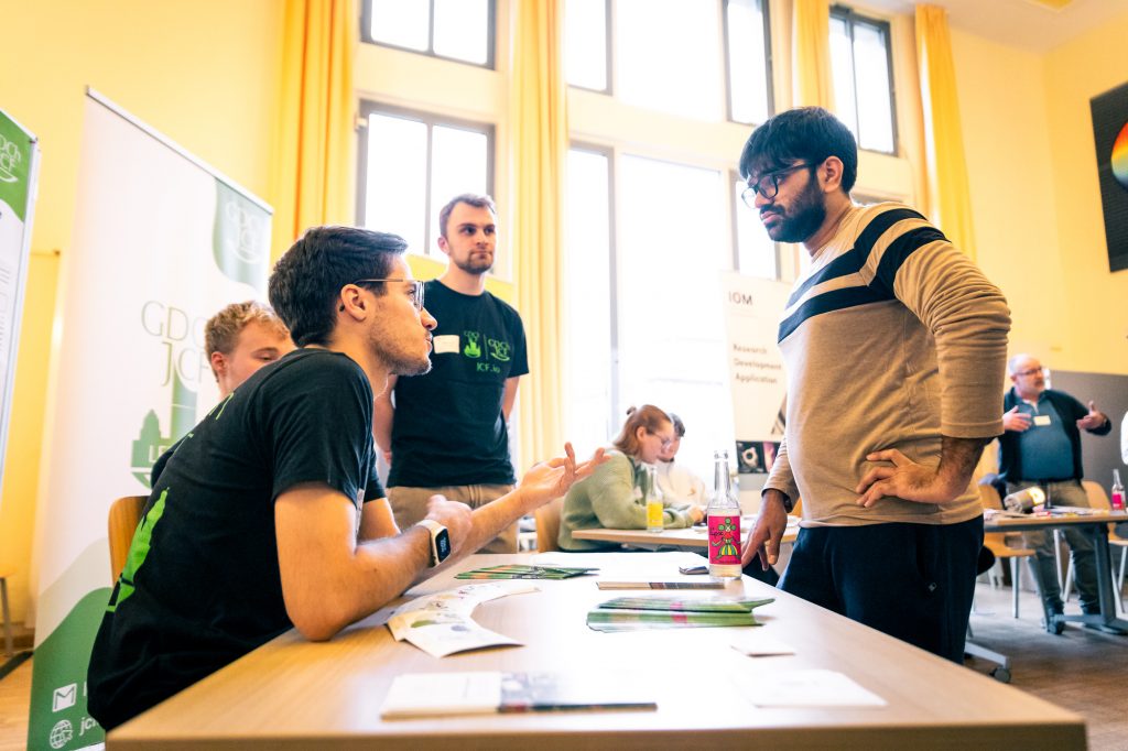 Junge Menschen reden an einem Tisch. Fotoreportage und Eventfotografie.