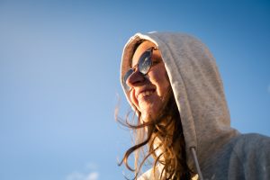 Portrait einer Frau mit Sonnenbrille vor strahlend blauem Himmel.