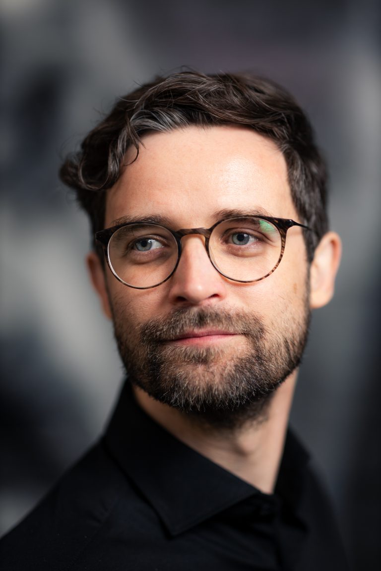 Ein junger Mann im Portrait. Dunkle Haare, Brille, er sieht ein wenig aus wie Daniel Radcliff. Portraitfotografie in Leipzig.