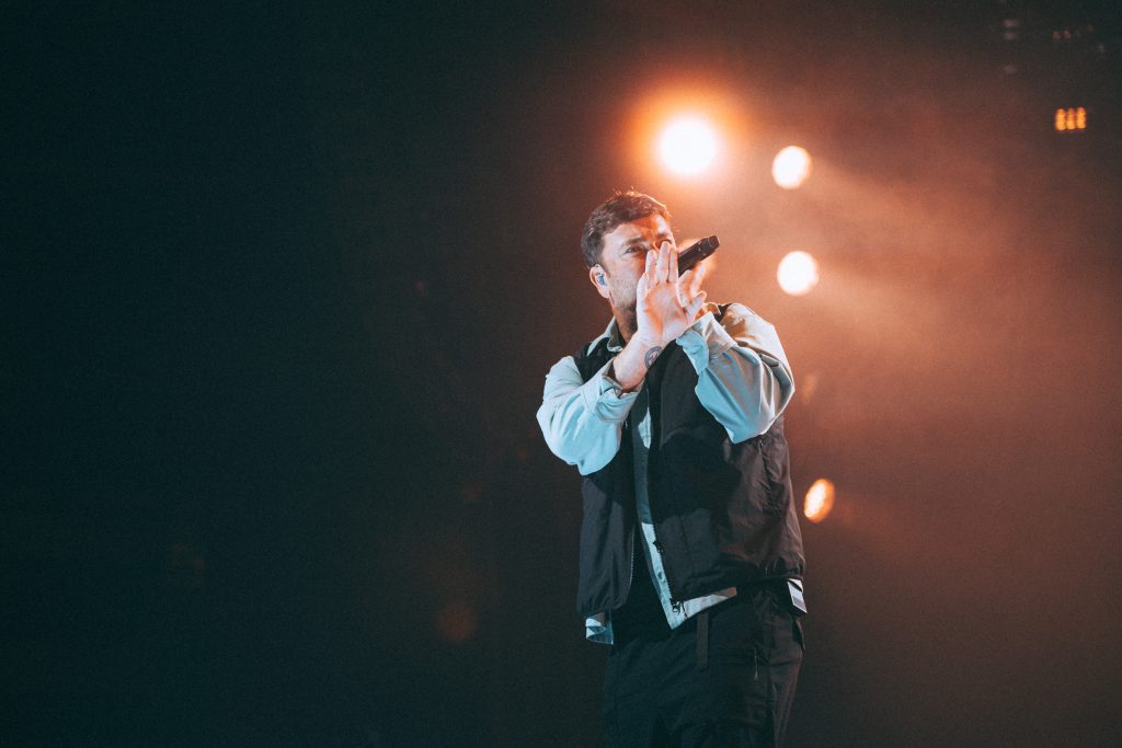 Marteria Konzert Leipzig: Rapper mit beiden Händen am Mikrofon vor orangefarbenen Scheinwerfern