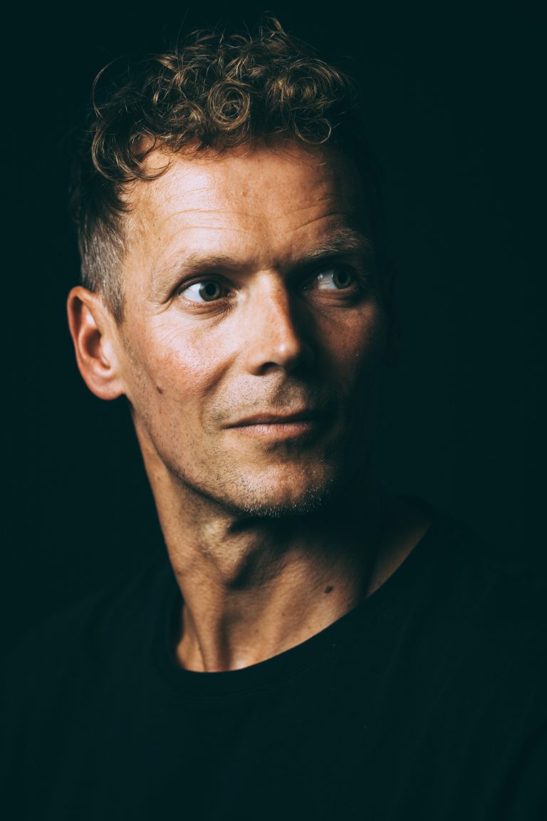 Authentische Portraits in Leipzig: nachdenklicher Headshot eines Mannes, Blick leicht zur Seite, dunkles Studiosetting
