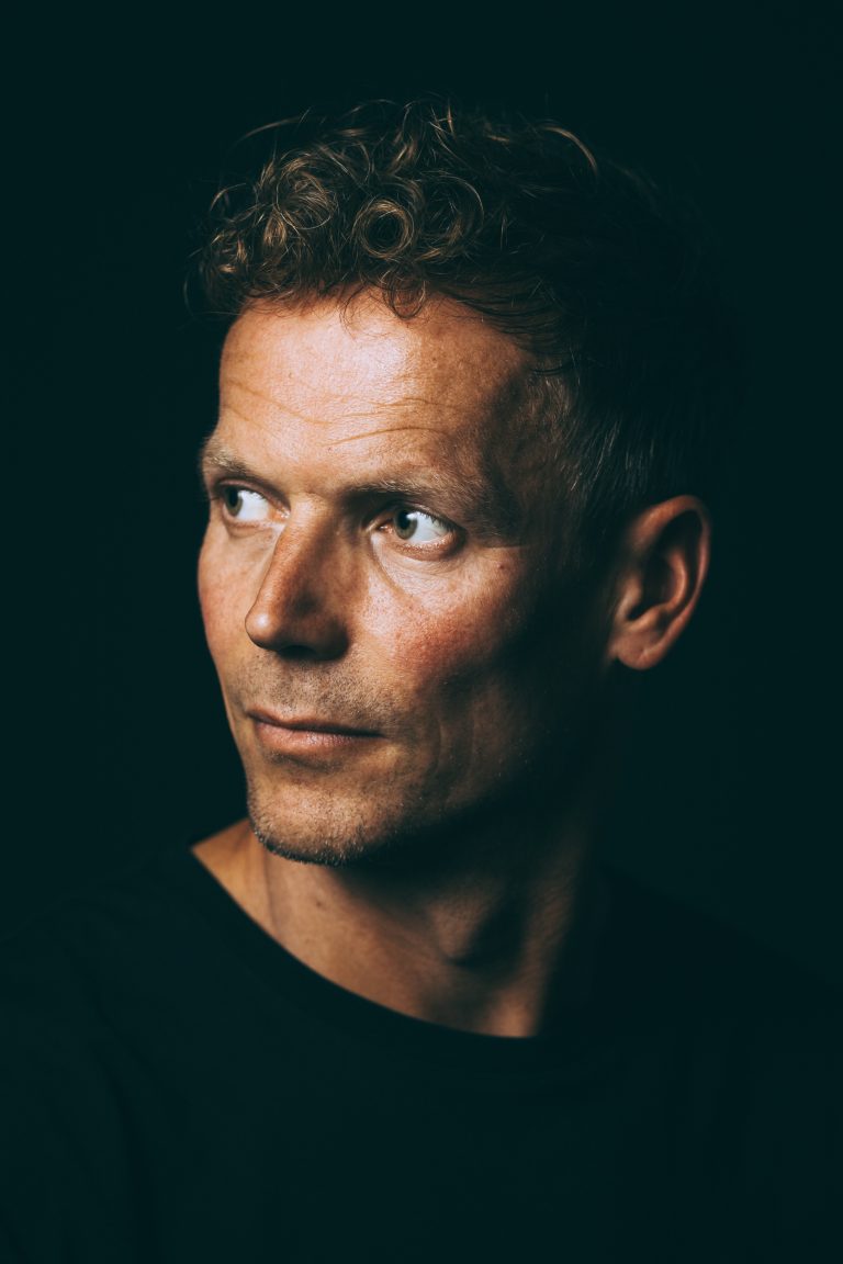 Ehrliches Studioportrait eines Mannes, ruhiger und zugleich zielbewusster Blick, dunkle Atmosphäre, Portraitfotograf Leipzig